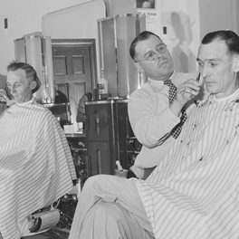Shop detail: barbers at work over customers in a 1940s barbershop.