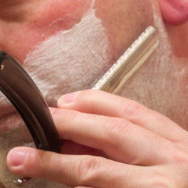 Shop detail: a straight razor drawn along a lathered jaw.