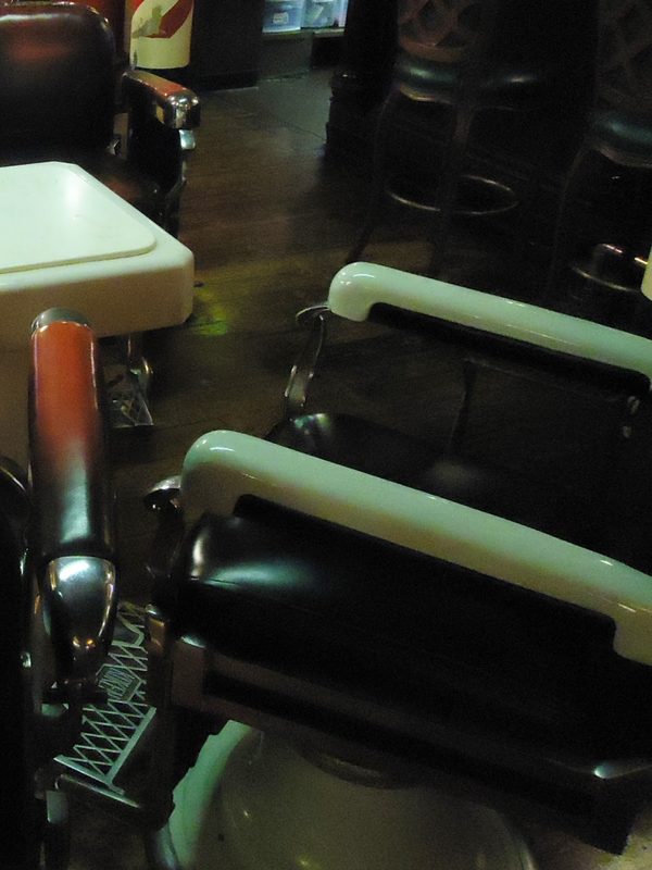 A row of reclining barber chairs with white enamel arms