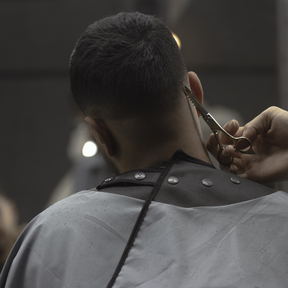 Shears working at the nape of a caped client's head.