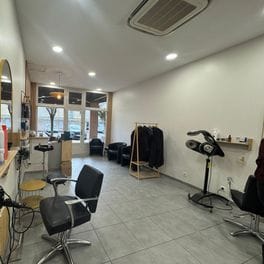 Salon detail: a black styling chair beside a hood dryer on a stand.