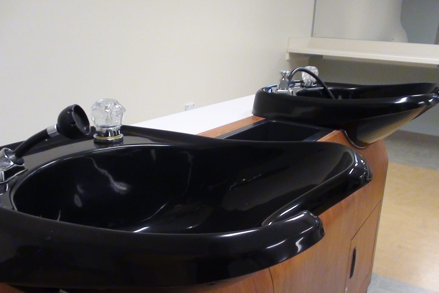 Two black backwash basins set into a wooden unit.