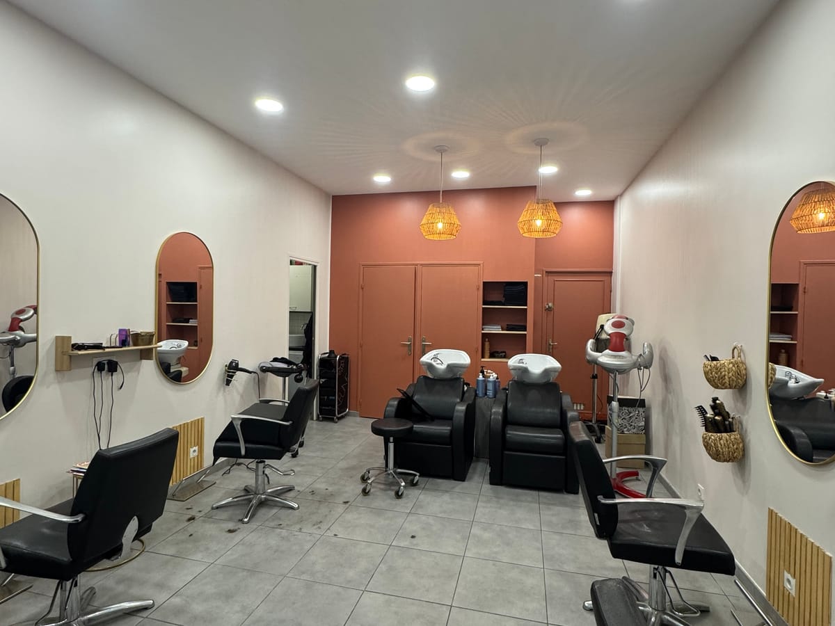 A salon cutting station with a chair, a mirror and styling tools set out on the counter.