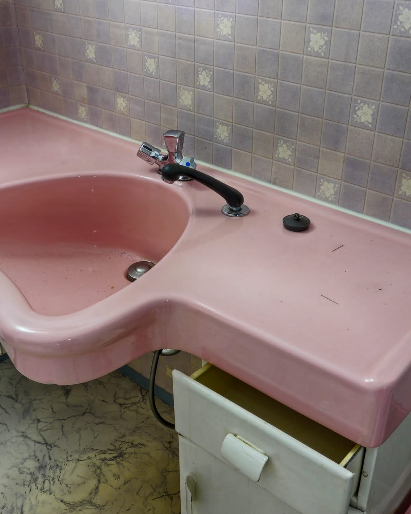 A pink salon wash basin with a chair set in front of it, from a 1970s salon interior.