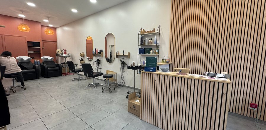 The front room of the studio: reception counter, slatted-wood screen and styling chairs