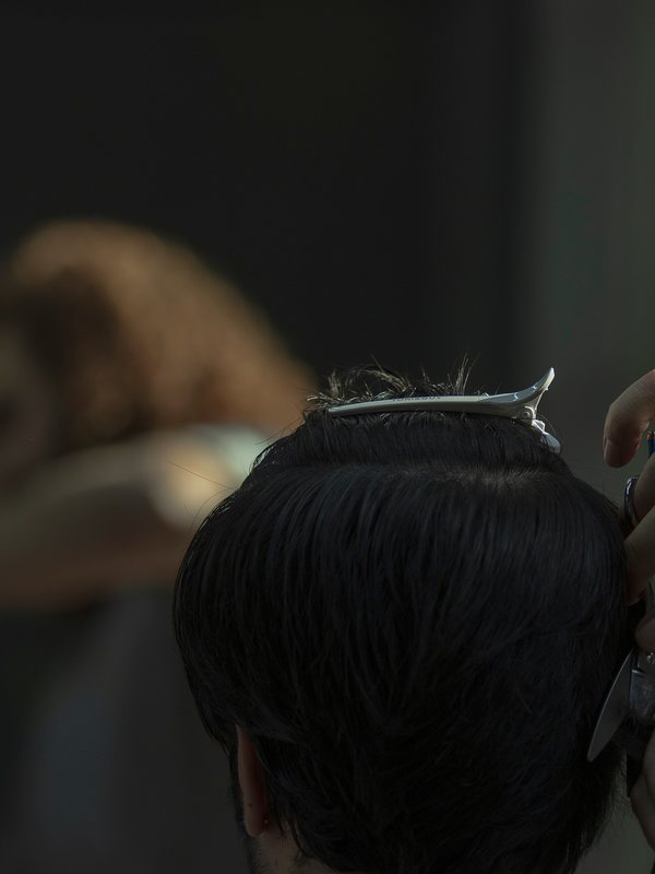 A stylist cutting into the back of a client&rsquo;s hair with shears and comb