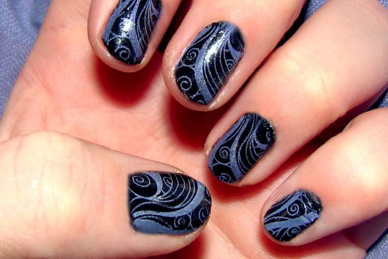 Nails in purple and white with a swirled stamped pattern across the tips.