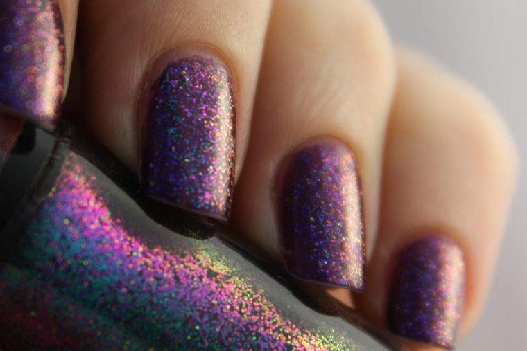 A hand with nails in purple glitter polish, the fingers slightly curled.