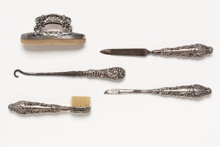 An old manicure set laid open, with steel files, nippers and a buffer in fitted slots.