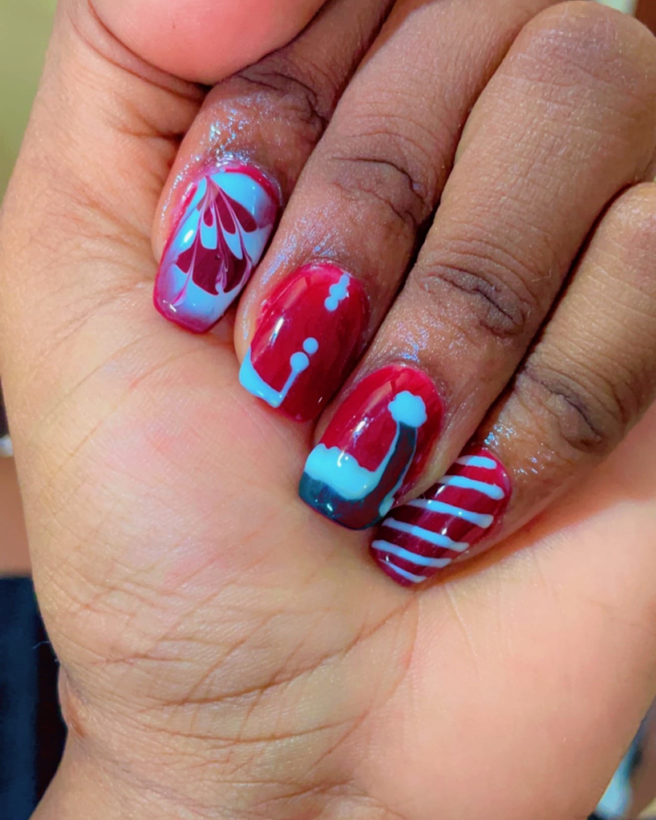 A hand with nails painted in bright red and blue freehand patterns.