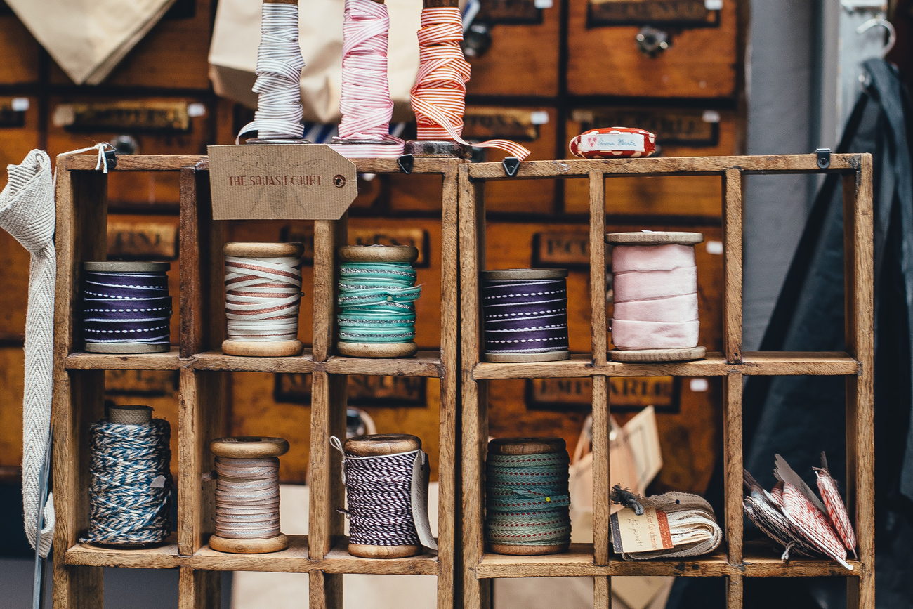A wall of wooden thread spools in many colours, stacked in rows on a workshop rack.