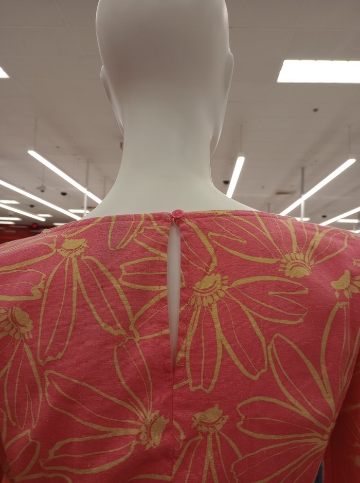 A hand-finished button closure at the back of a neckline