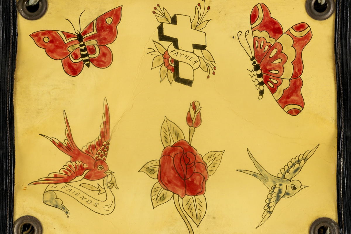 A hand-painted flash sheet: butterflies, swallows, a rose and a lettered cross, laid out in rows.