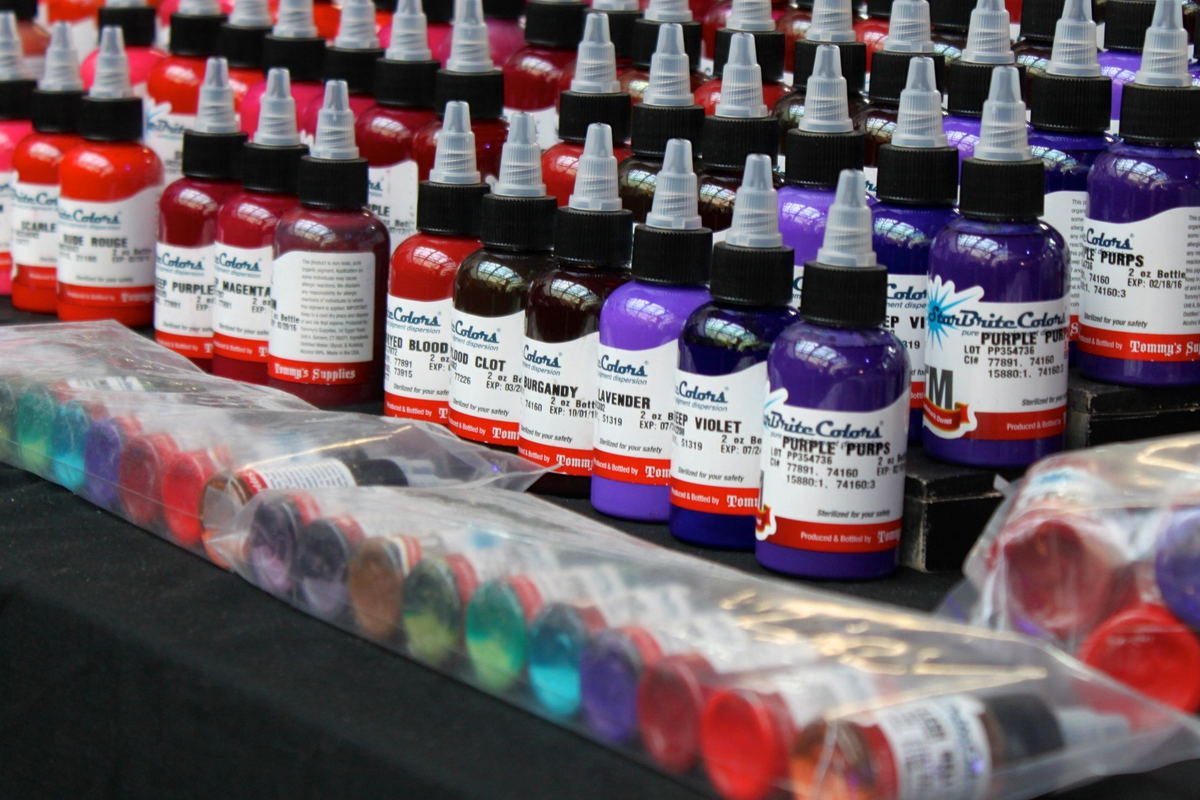Rows of ink bottles ranked on a shelf with their caps upward.