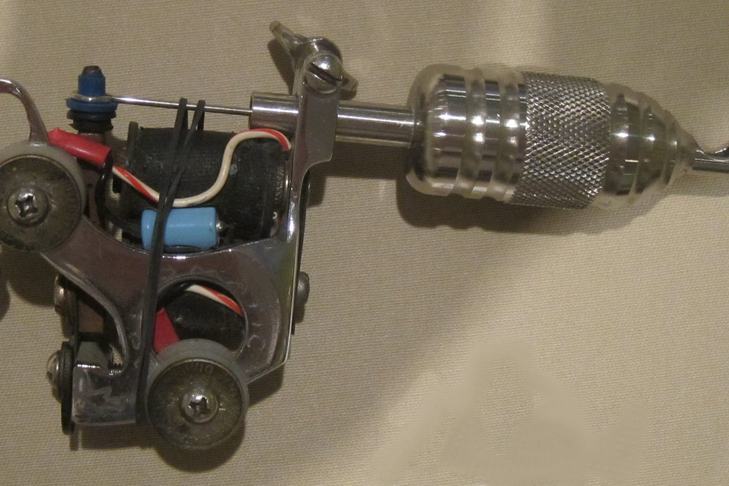 A tattoo machine photographed closely with its frame and grip visible.