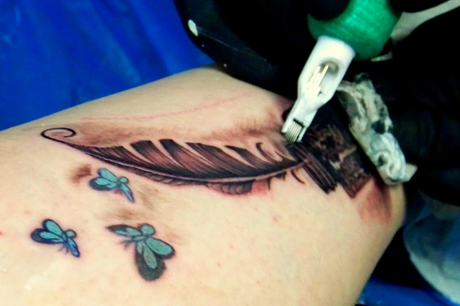 A fine-line feather outline taking shape under the machine
