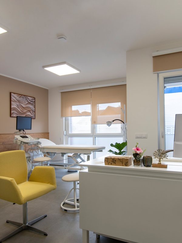 Bright treatment room with a padded couch, adjustable lamp and a yellow chair