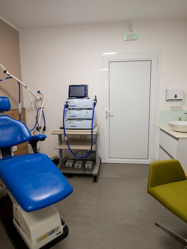 Clinical room with a blue treatment chair and an equipment trolley