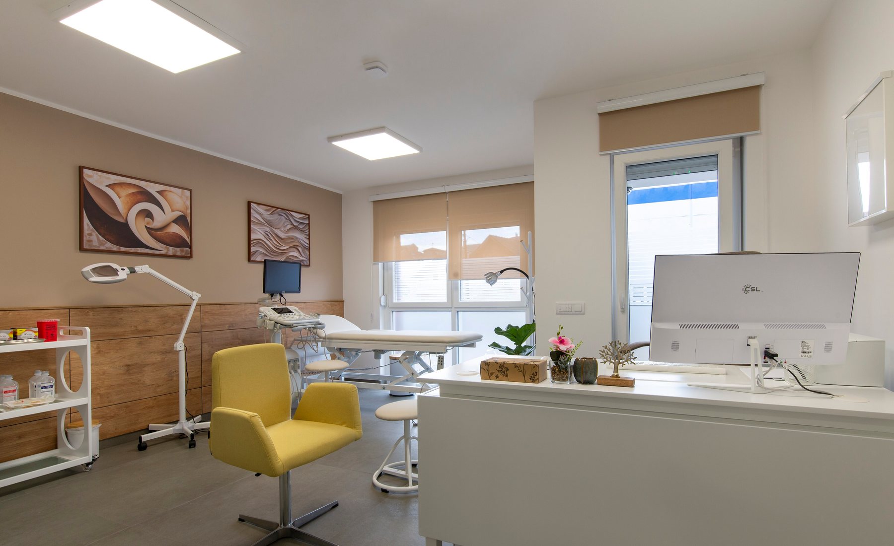 Bright treatment room with a padded couch, adjustable lamp and a yellow chair