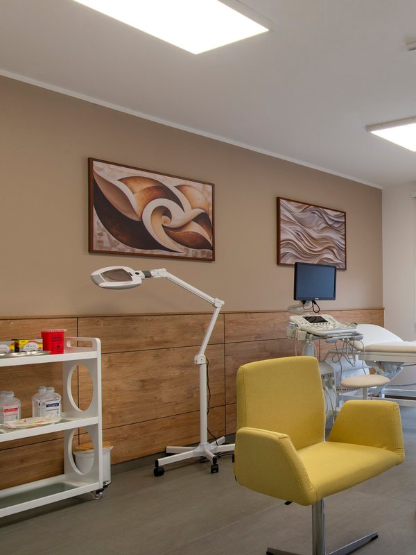 MedSpa room with a magnifying lamp, yellow consultation chair and treatment couch