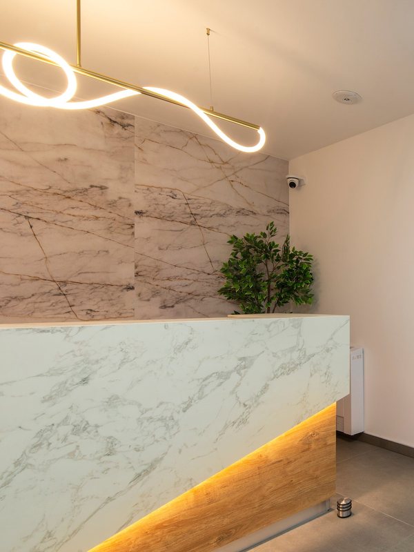 Marble reception counter with a plant and a ring pendant light above