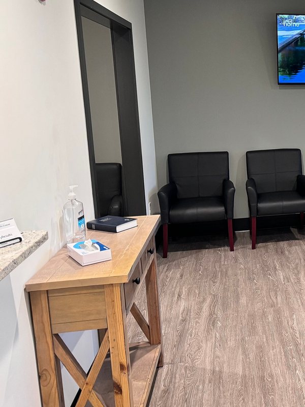 Waiting area with a side table, hand sanitiser and upholstered chairs