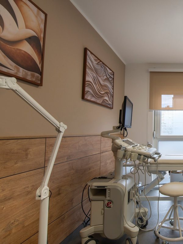 Consultation room with an examination lamp, wall art and a treatment couch by the window