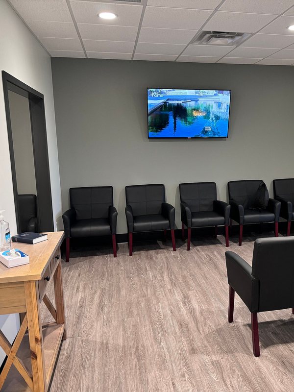 The waiting lounge, with seating along the wall and a wall-mounted screen