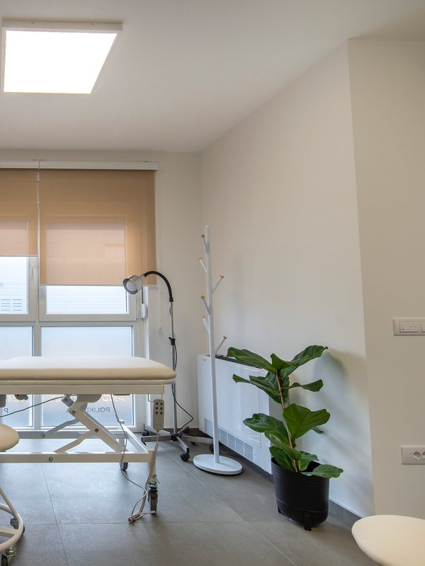 Corner of an examination room with a coat stand and a potted plant