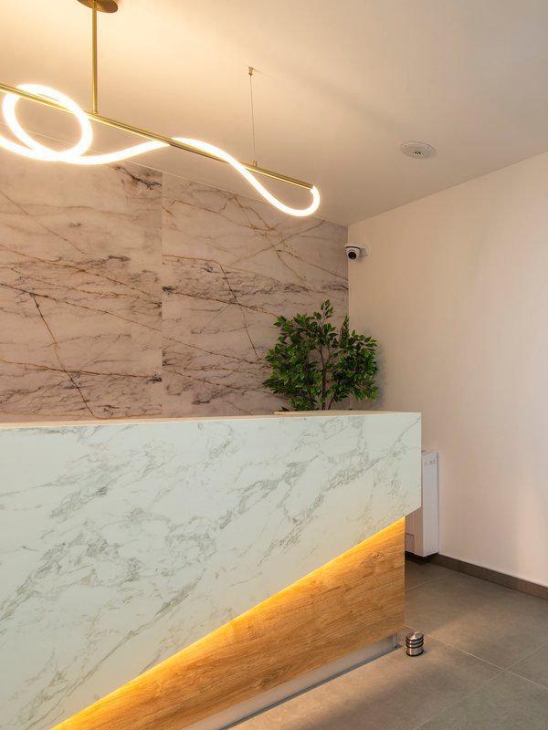 Marble reception desk beneath a brass pendant light
