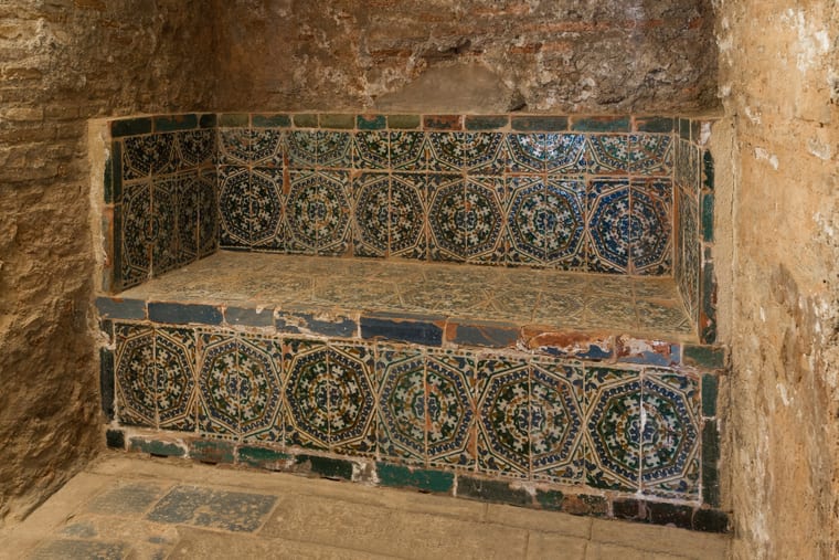A stone bench set into a tiled wall in a domed bathing room.