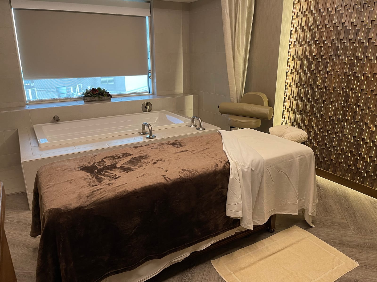 A treatment room with a massage table made up under a low warm light.