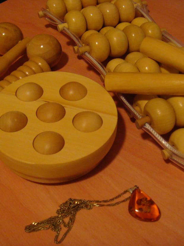 Wooden massage rollers and a shaped hand tool laid out on a cloth.