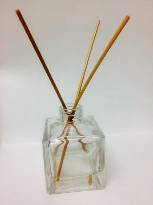 A reed diffuser with thin reeds standing in a clear bottle.