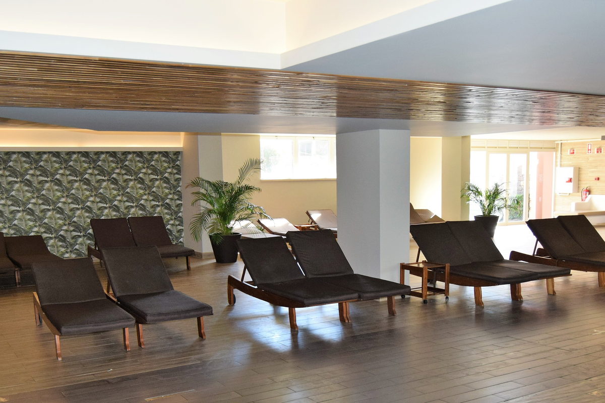 A spa interior with loungers set along a wall of windows.