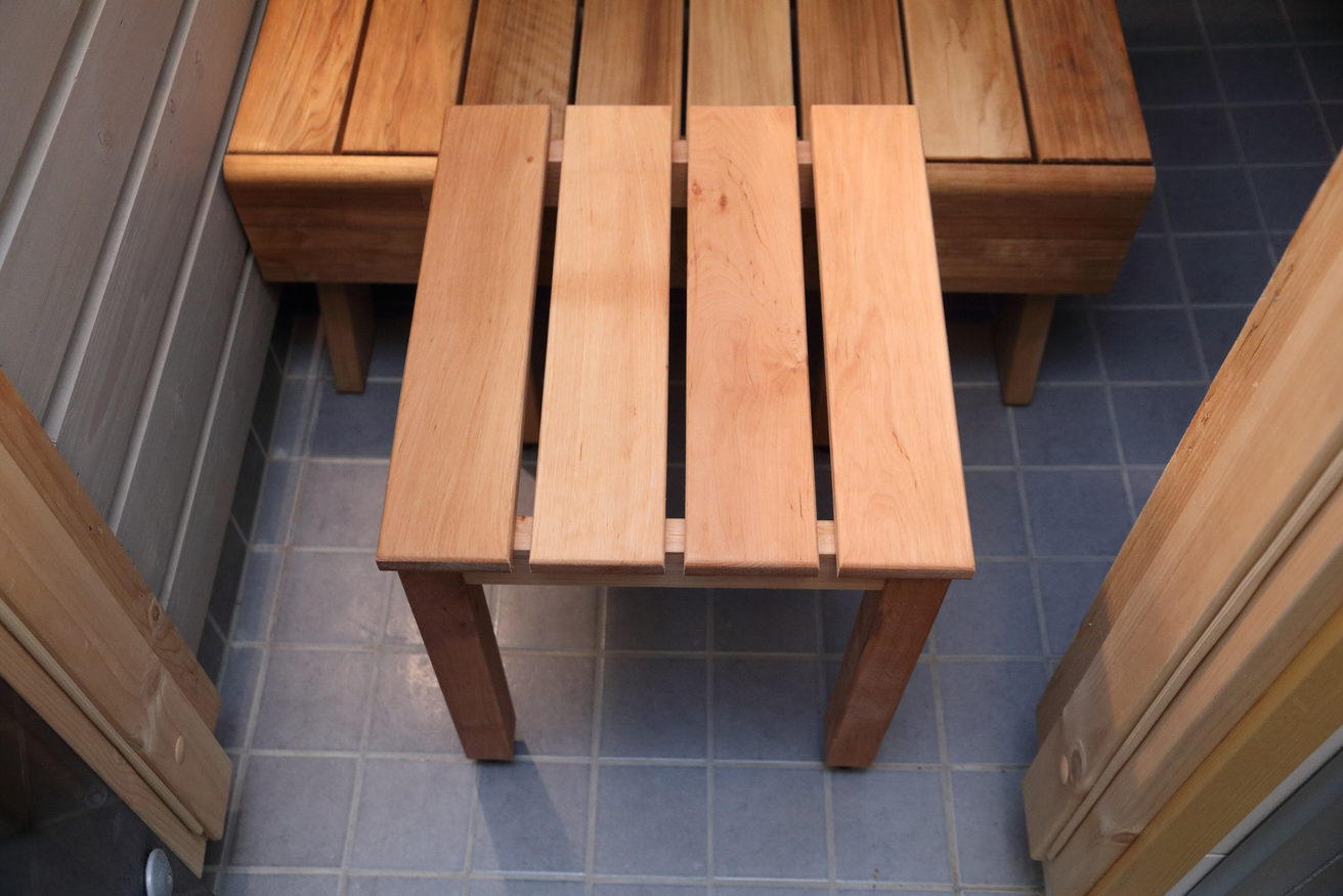 A plain wooden stool standing on a slatted floor.