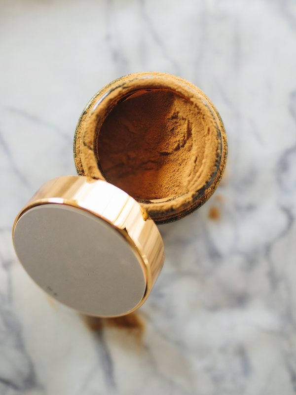 An open brass pot of mineral powder on marble