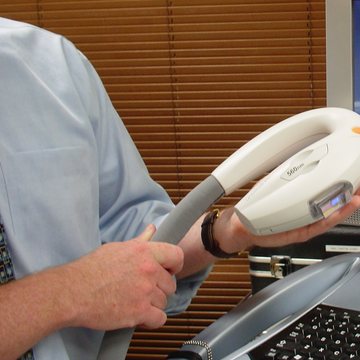 A clinician holding an IPL handpiece in a treatment room