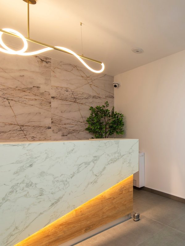 The marble reception desk under a curved pendant light