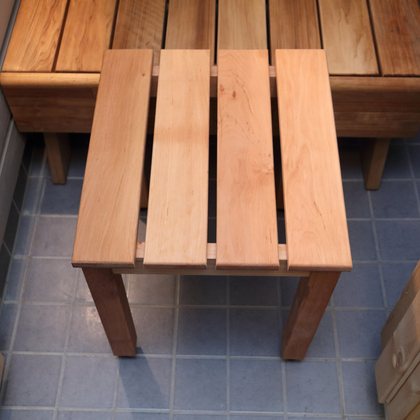 A plain slatted wooden stool on a tiled floor in the changing room