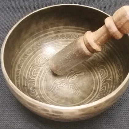 A hammered singing bowl with its wooden striker resting inside