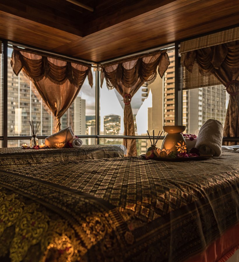 A therapy room made up with fresh linen, incense and rolled towels, looking out over the city