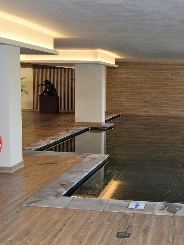 A long indoor room with a shallow still-water channel and warm cove lighting