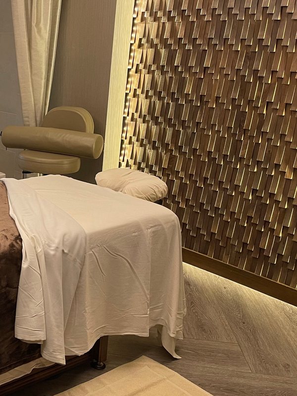 Massage couch draped in white against a textured gold-tile wall