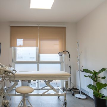 Examination couch and ultrasound scanner by a bright window, with a coat stand and a plant