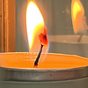 A lit candle flame in a glass jar