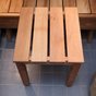 Slatted wooden sauna stool on a tiled floor