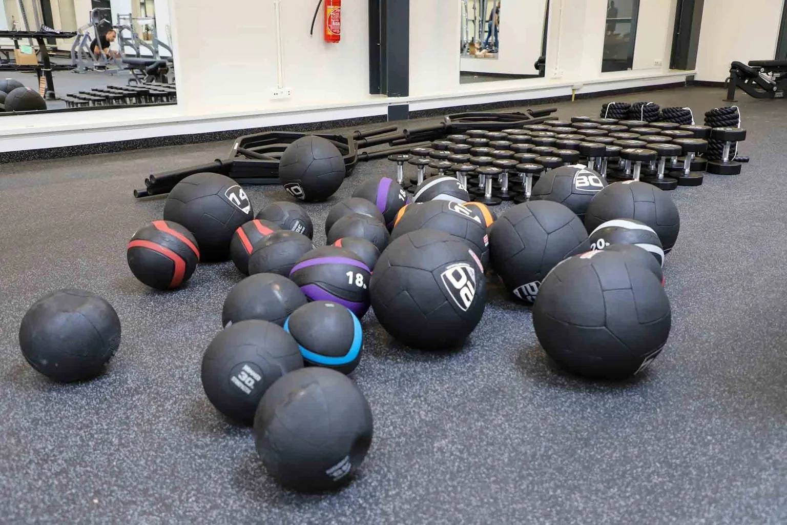 Medicine balls and dumbbells set out on a conditioning floor