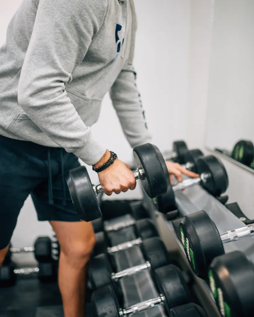 Anonymous lifter taking a dumbbell from the rack