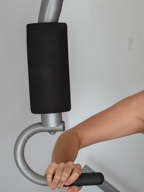 The padded arm, pivot and grip handle of the chest-press station in the machine room